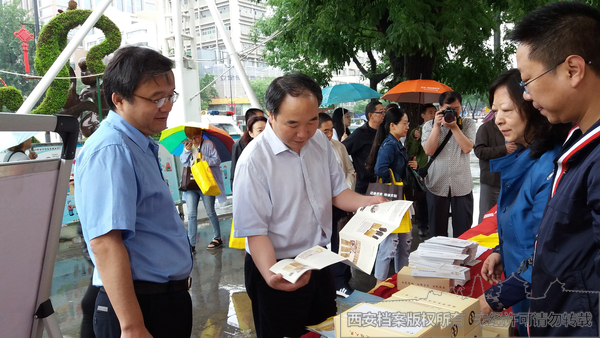 西安市档案局副局长吴立民（左二）、未央区副区长李亚省（左一）翻看宣传册