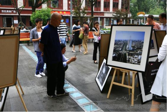 市民驻足观看城市发展对比照片