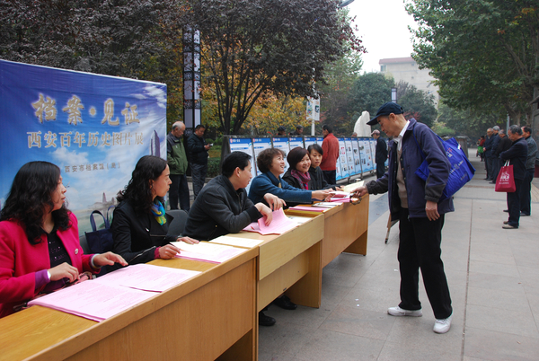 市档案局副局长黄海绒（左四）向灞桥区观展市民发放档案法制宣传材料